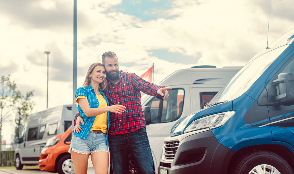 Couple looking for camper or RV on yard of dealer