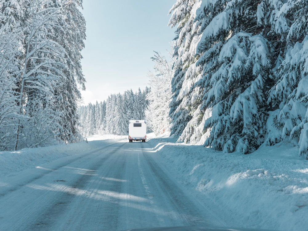 RV camper driving down a snowy road during winter after RV winterization service