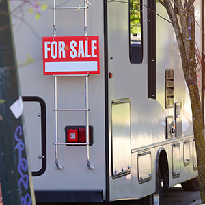 A "For sale" sign hangs on an RV to tell you about great RV Black Friday Deals on campers