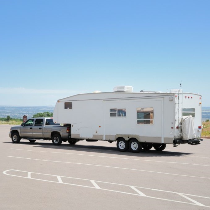 Travel trailer parked in a parking lot for overnight RV parking.