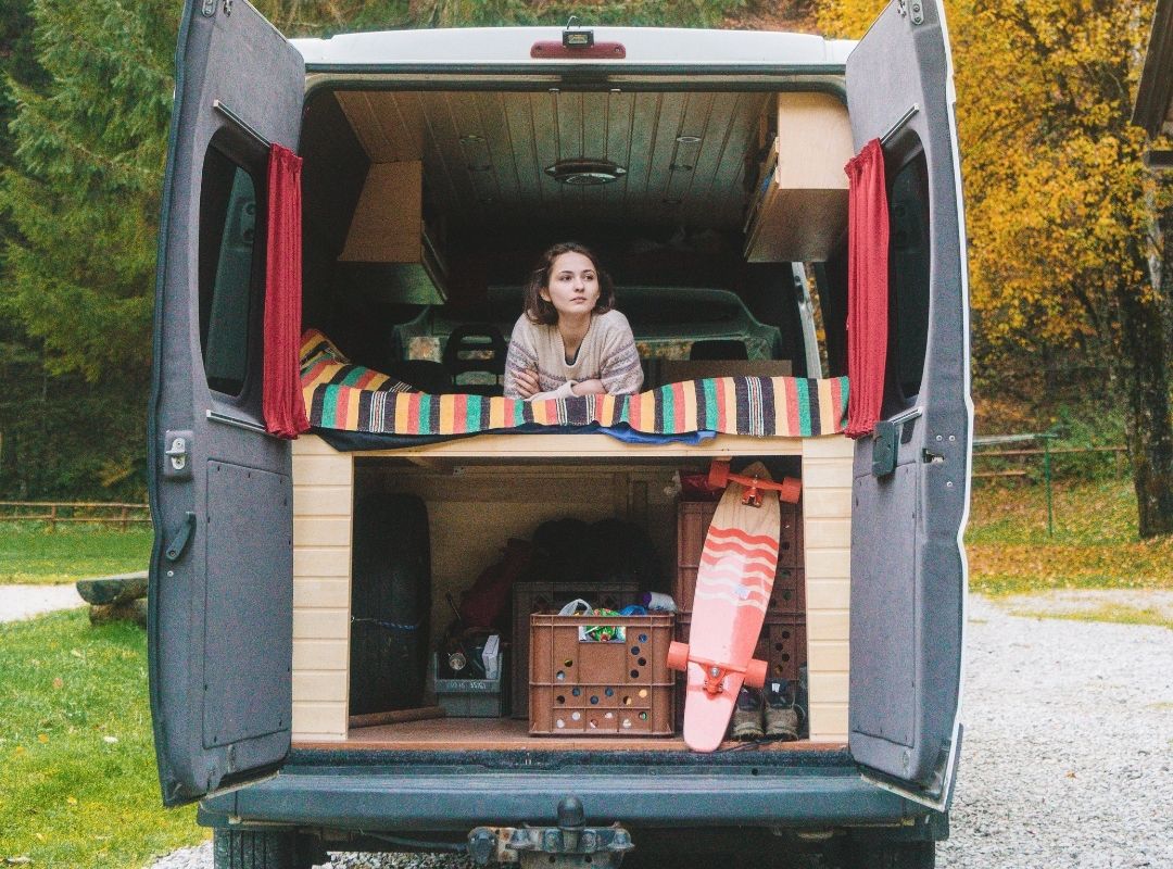 Conversion van girl sitting in the top rack of her conversion van