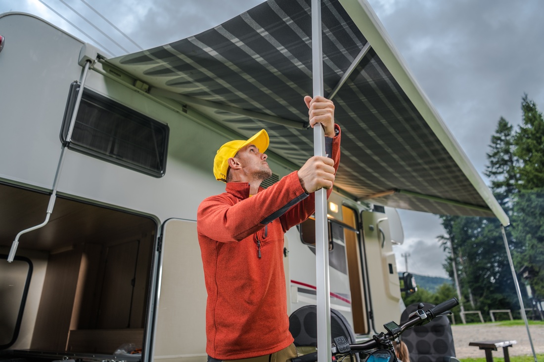 Man Extending RV Awning RV Motorhome Awning Extending by Caucasian Camper in His 30s. Travel Industry.