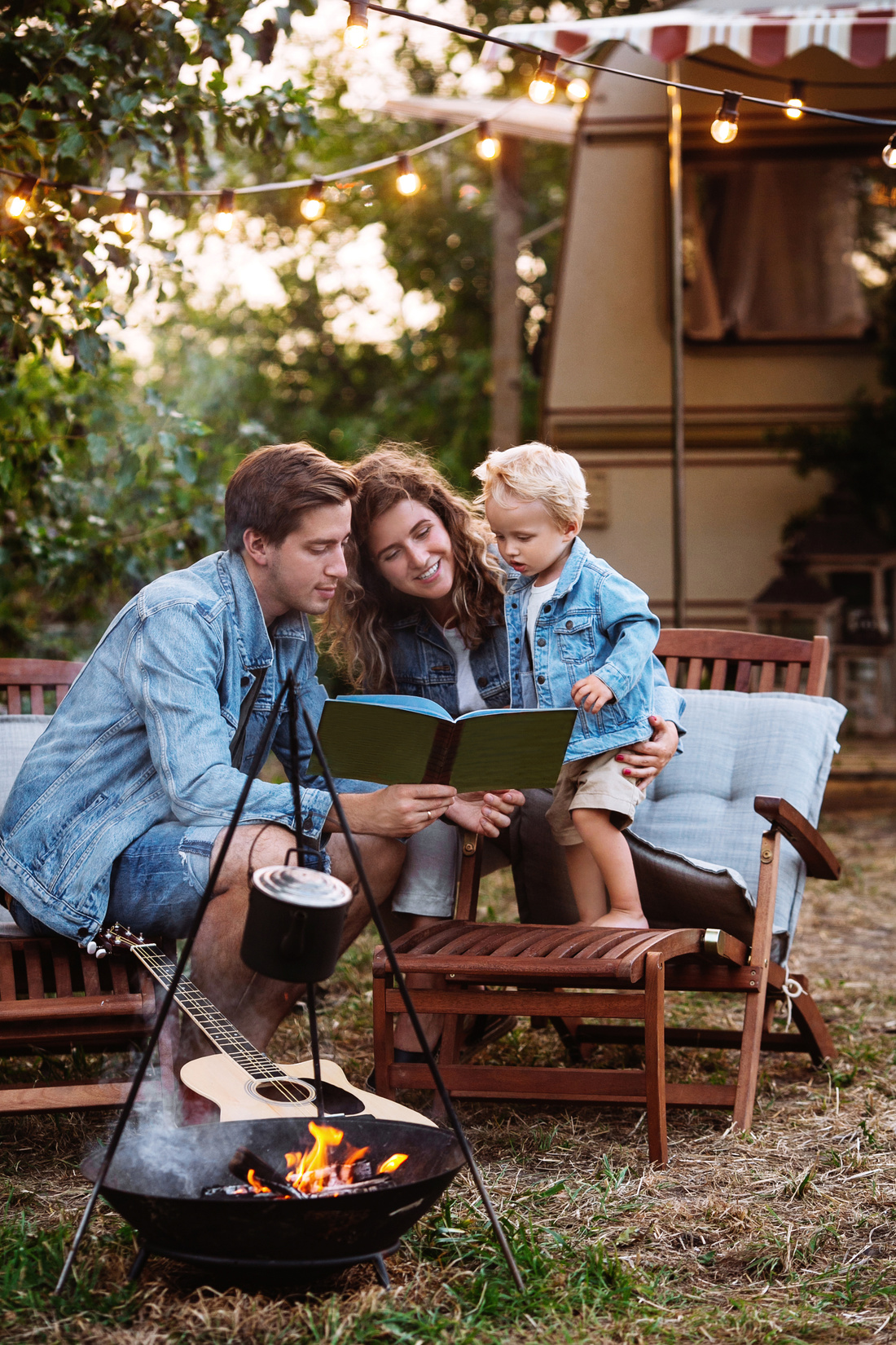 A family reading a book, from our RV packing list, by a campfire. 