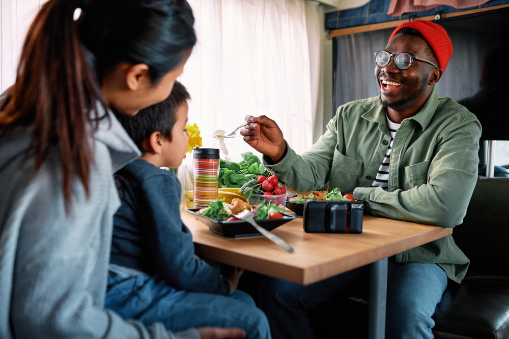 A young family of three eats at the dinette table in their motorhome.