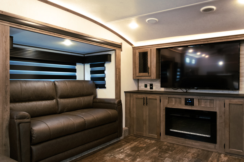 RV Interior Living Room The living room in one of many fifth wheels with front living rooms. A couch, fireplace and TV are visible.