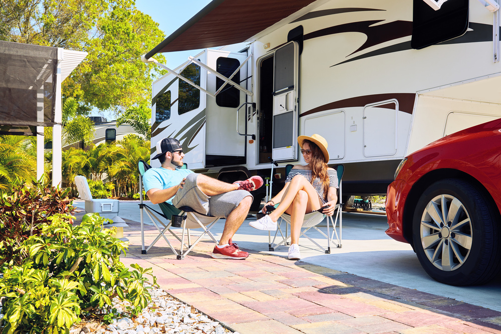 Couple sits at their campsite in front of their fifth wheel.