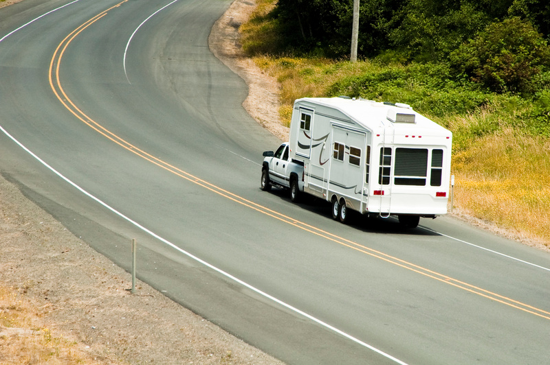 A white truck tows a fifth wheel down the highway.