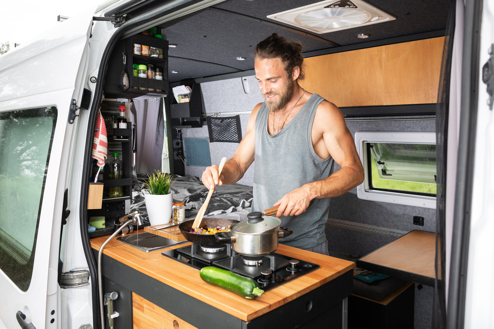 man cooking inside conversion camper van