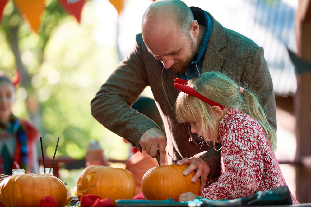 father and daughter carving a pumpkin together
