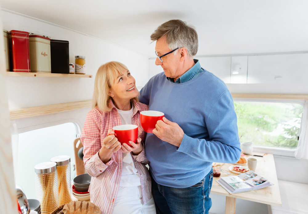 Happy couple inside their new RV drinking coffee