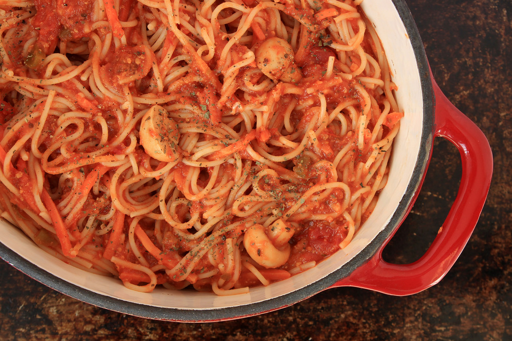 Spaghetti with tomato sauce and vegetables in red Dutch oven