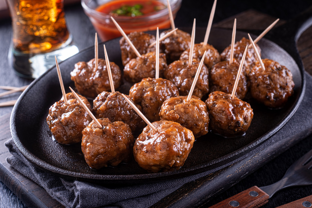 a tray of meatballs on a stick