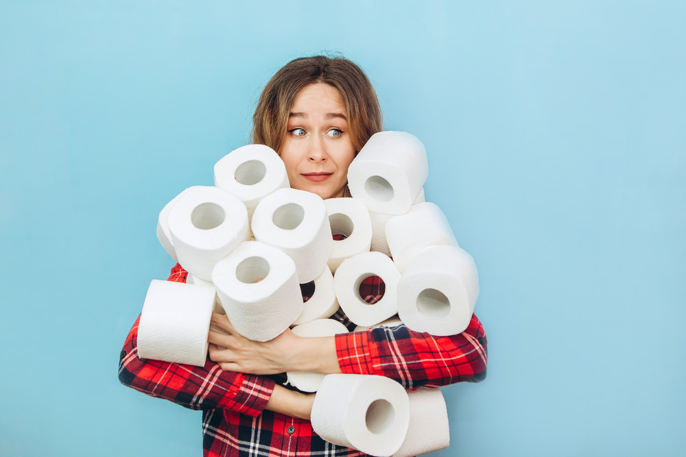 Girl with a lot of rolls of RV toilet paper in her hands on a blue background.