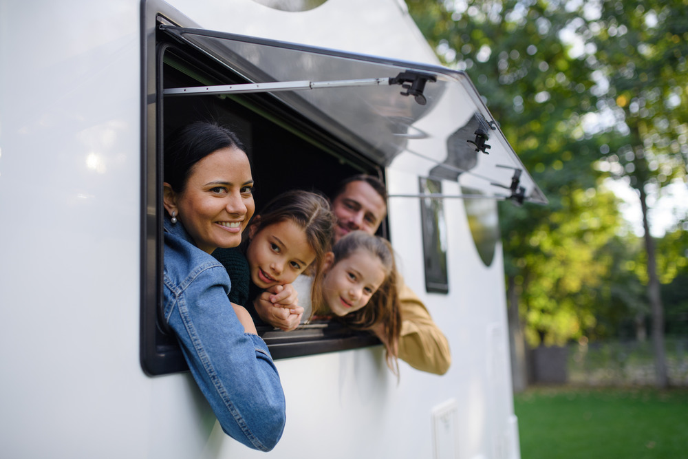 Happy young family with two children looking out of an affordable rv