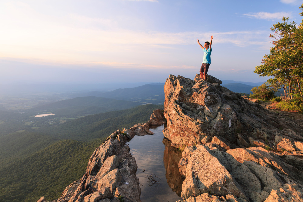 A teenager standing on the edge of a cliff in Shenandoah National Park