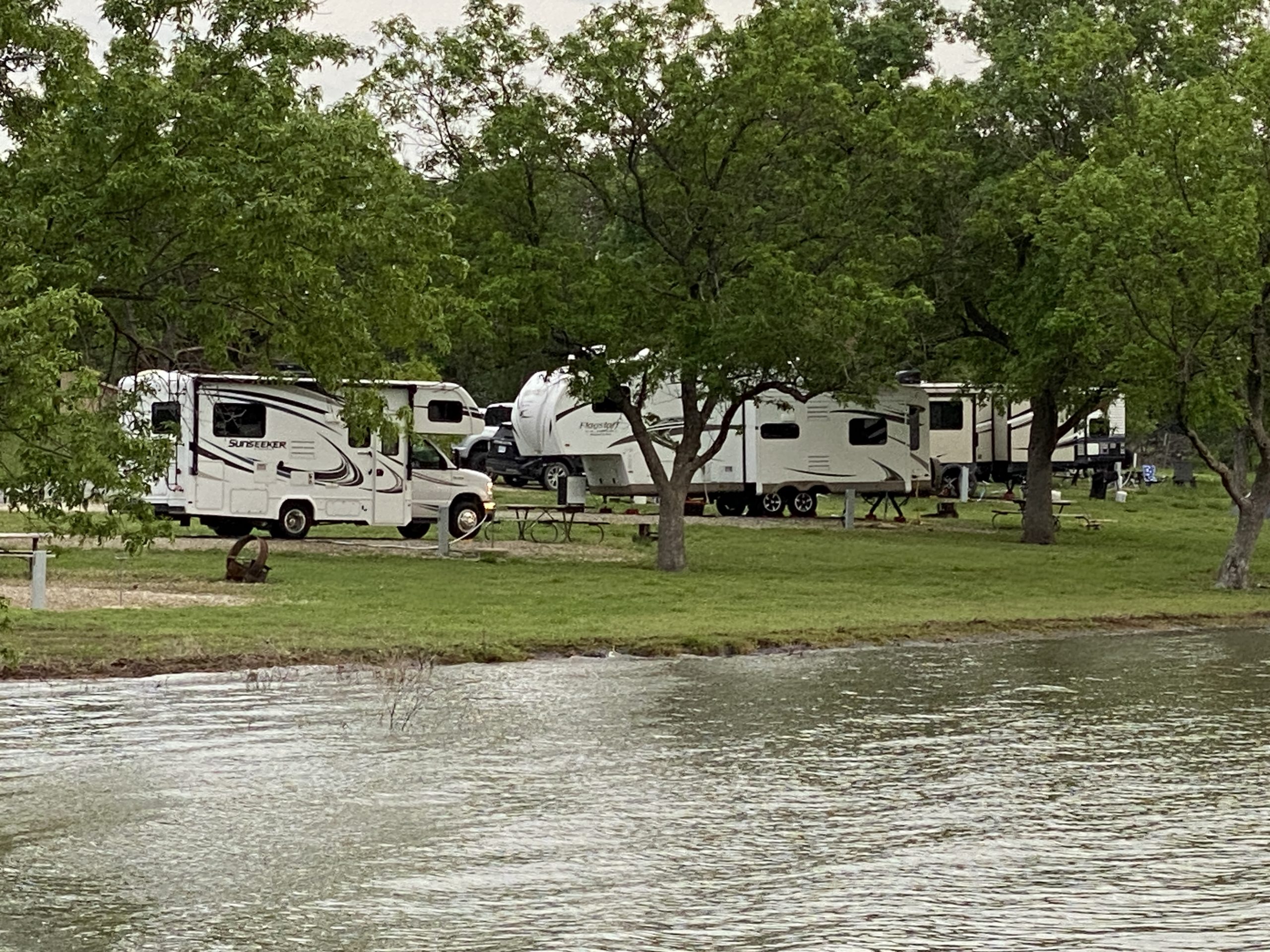 Motorhomes and towable RVs parked at an RV campground across a lake.