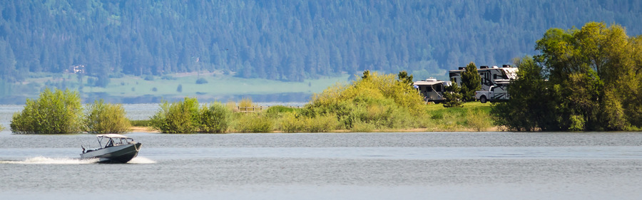 Boat speeding across the water with the RVs at camp in the distance