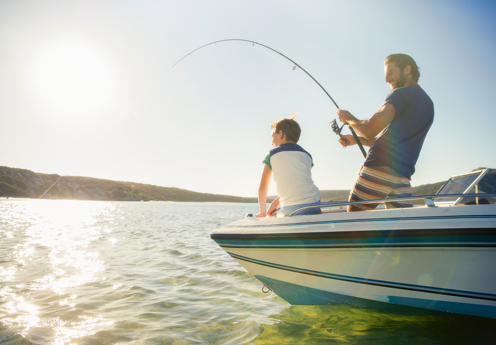 Father and son fishing on boat while at a rv and marine campground