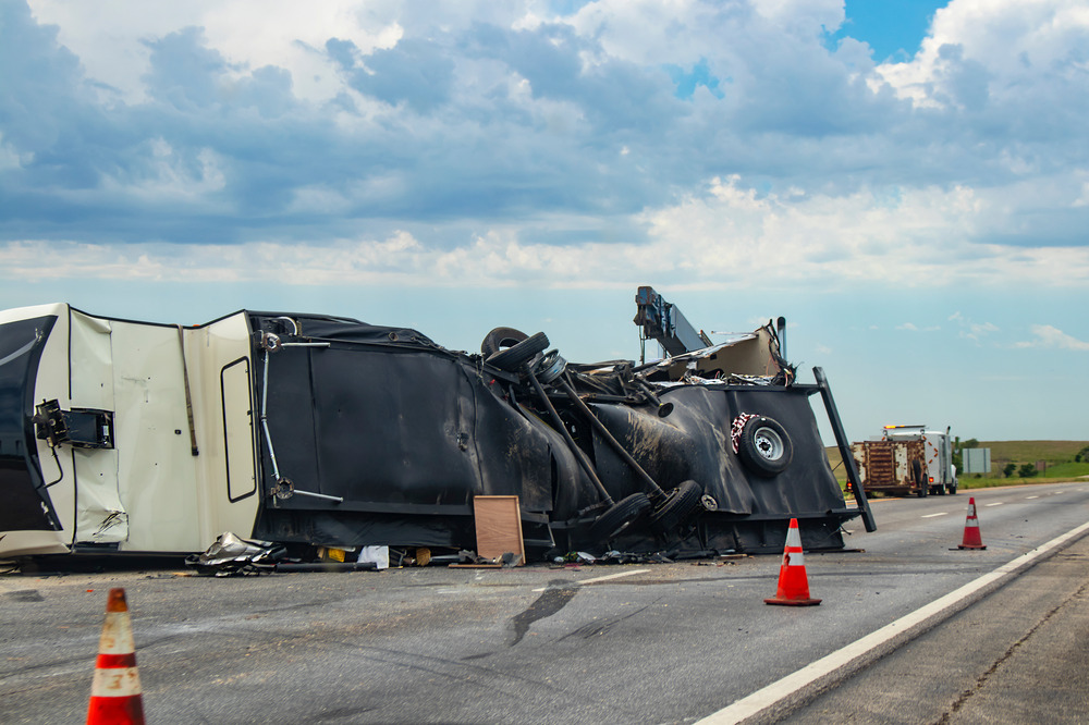 Fifth wheel RV overturned on a highway with the underside torn up and things spilling out into the roadway after an accident