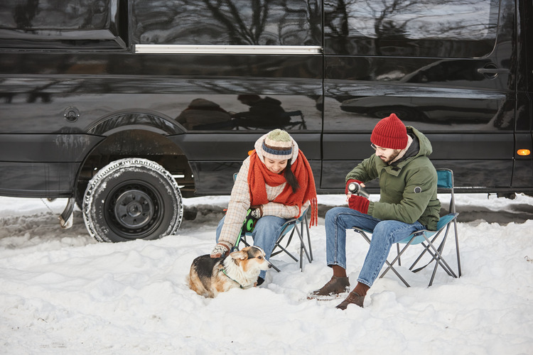 young couple RV traveling in winter with a dog