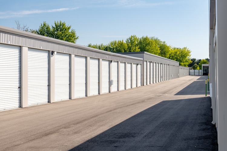 Row of enclosed rv storage units with garage doors with trees