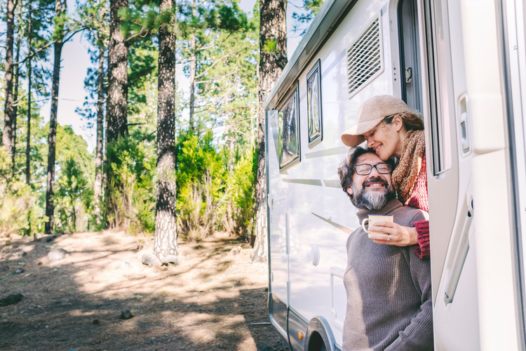 Happy people on travel lifestyle sitting on the door of a couples camper