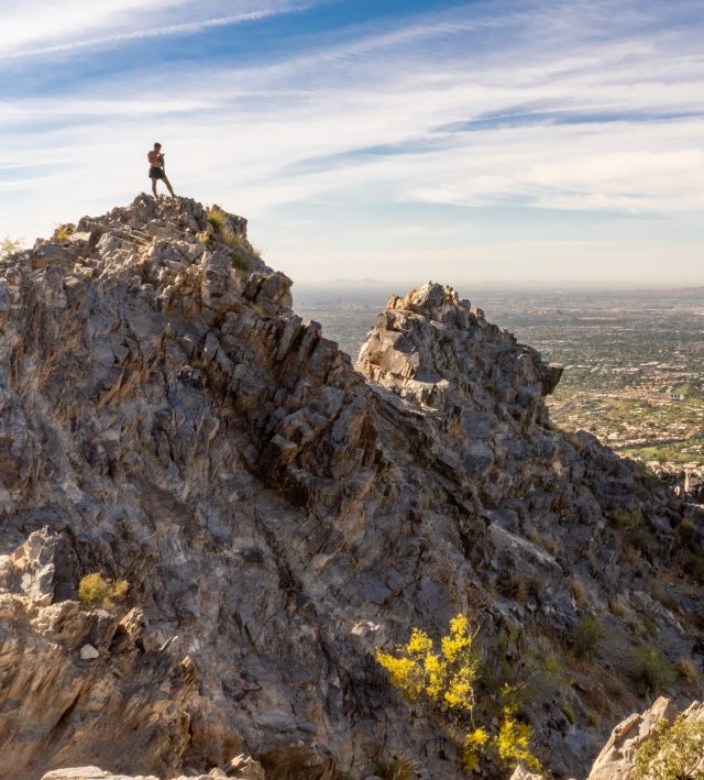 A lone hiker is seen atop Piestewa Peak in Phoenix, Arizona, on top of a rocky cliff overlooking the Valley