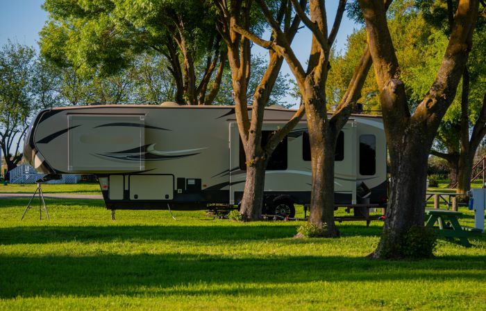 Fifth Wheel Campsite in Trees A fifth wheel on a grassy campsite in the trees.