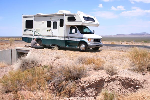 person fixing Motorhome RV with Flat in Desert