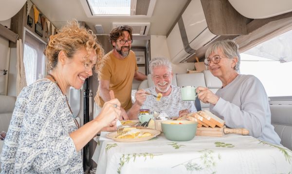 Happy family sitting inside an rv at the dinette enjoying a meal together