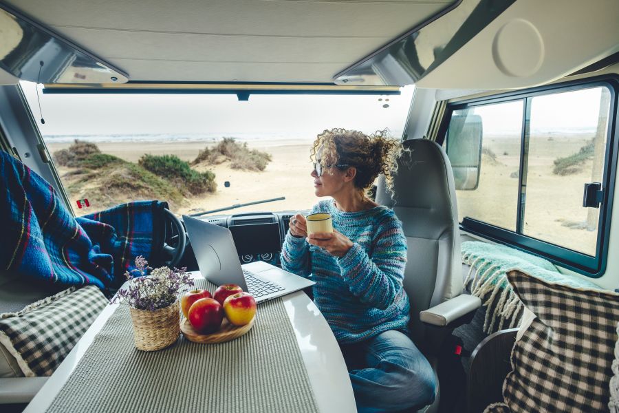  woman sitting in an RV enjoys relaxing and connecting to her laptop 
