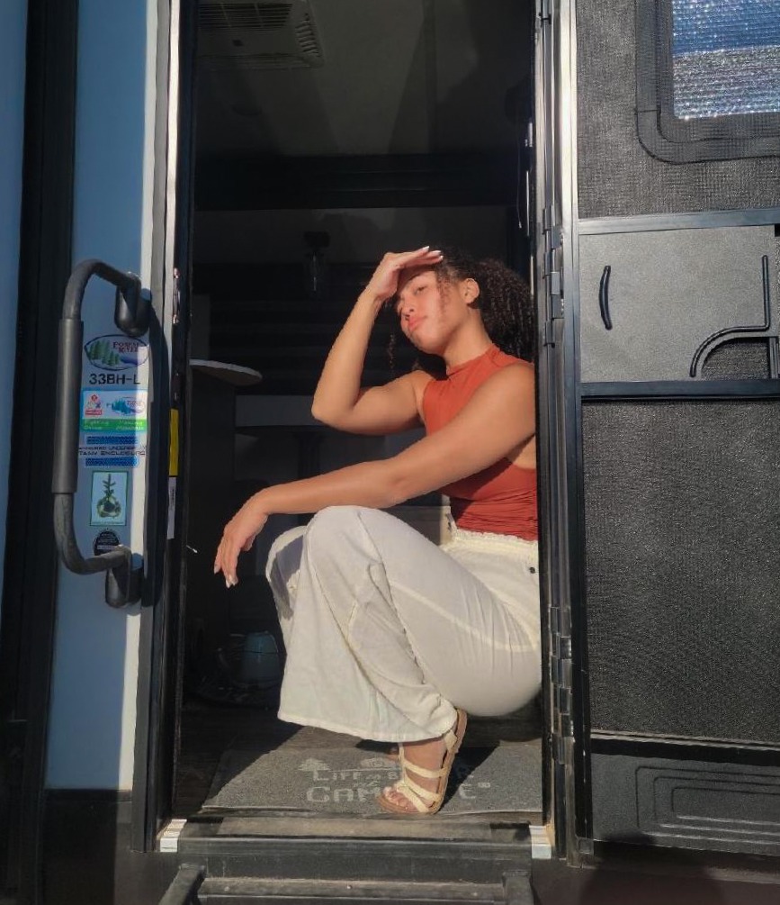 Carol of The Nomad Junkie sitting on the front entry steps of her RV.