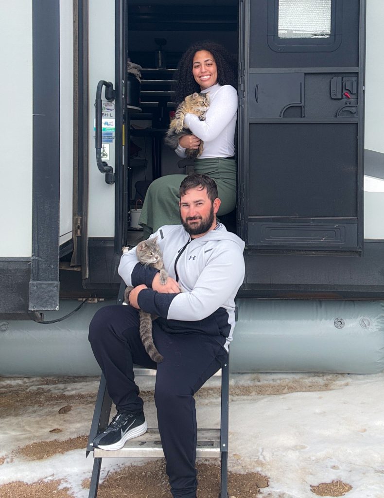 Jon, Carol, and their two cats on the steps of their RV.