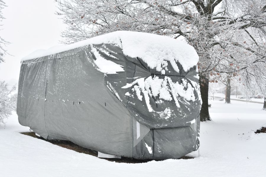 an rv covered in a tarp and snow