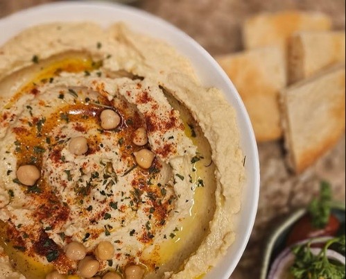 Seasoned hummus bowl with bread to dip. 