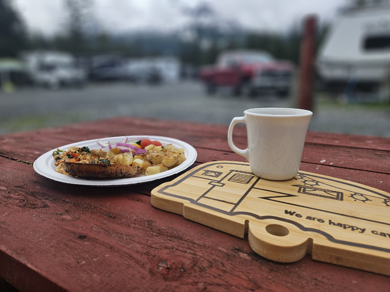 A vegan meal, mug, and RV-shaped cutting board on a table. 