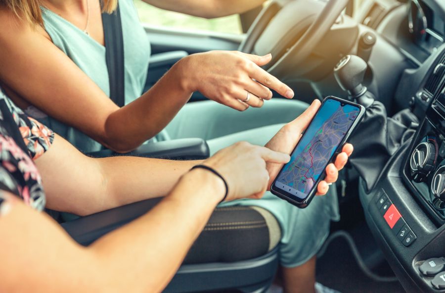 Female friends looking at the gps on the mobile during a trip<br />

